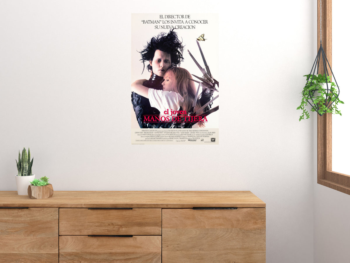 Edward Scissorhands Spanish-language movie poster displayed above a wooden sideboard beside a window and plants