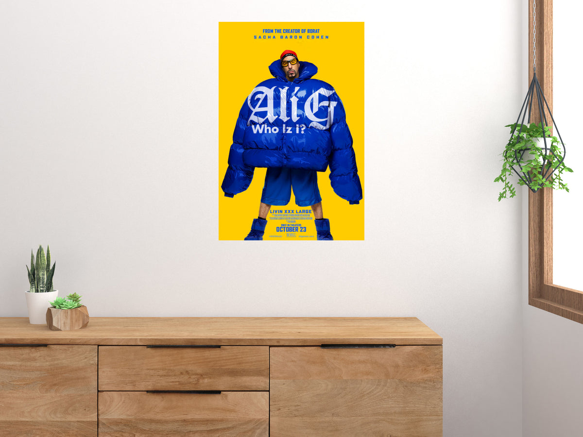 Ali G Who Iz I? poster displayed on a white wall above a wooden cabinet