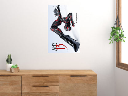 AHS 13 poster shown rotated vertically on a white wall above a wooden cabinet