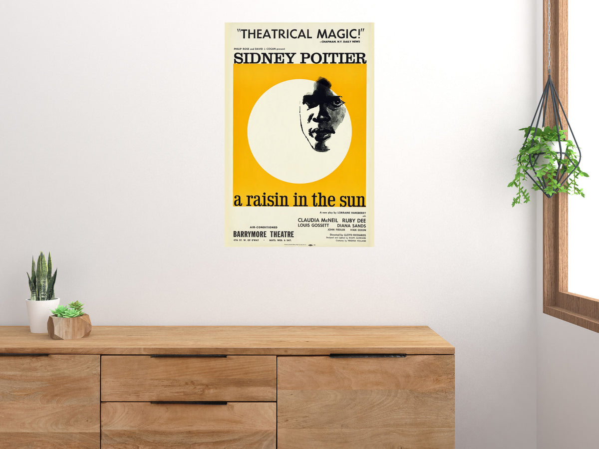 A Raisin in the Sun poster displayed on a white wall above a wooden cabinet