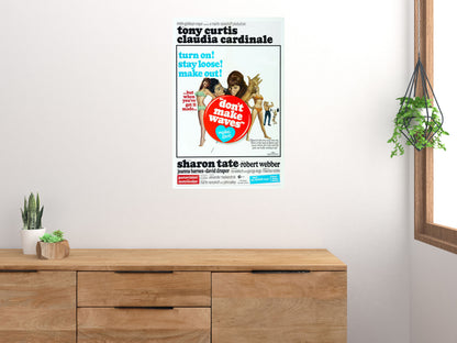 Don't Make Waves movie poster displayed above a wooden sideboard beside houseplants and a window