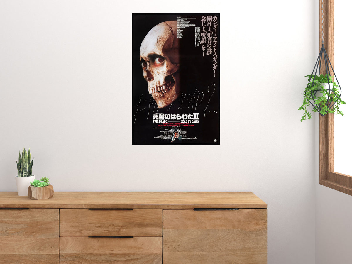 Evil Dead 2 Japanese skull poster displayed vertically above a wooden cabinet on a light wall