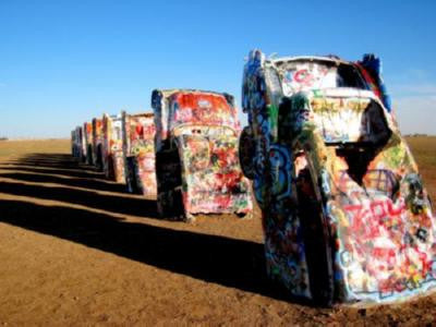 a row of painted cars sitting in the middle of a field